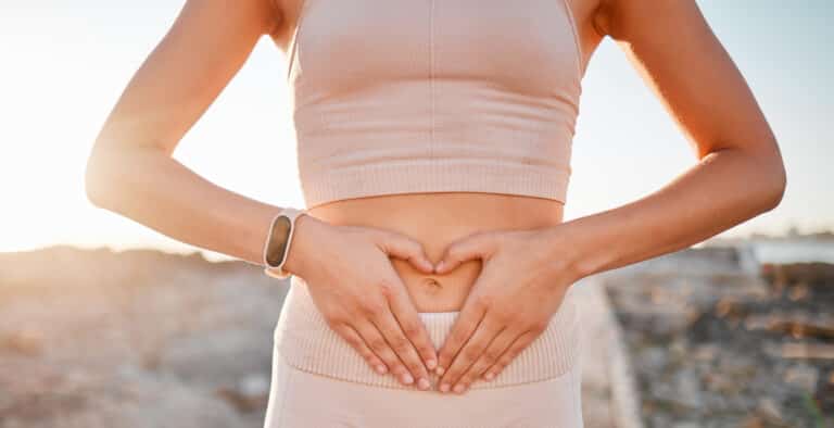 Woman, heart and hands on stomach for fitness, weightloss diet or holistic gut wellness
