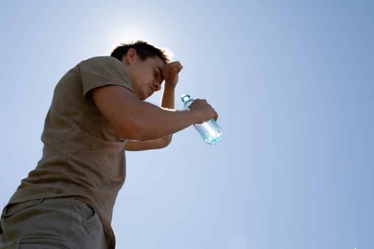 man drinking water feeling exhausted in the heat of the day