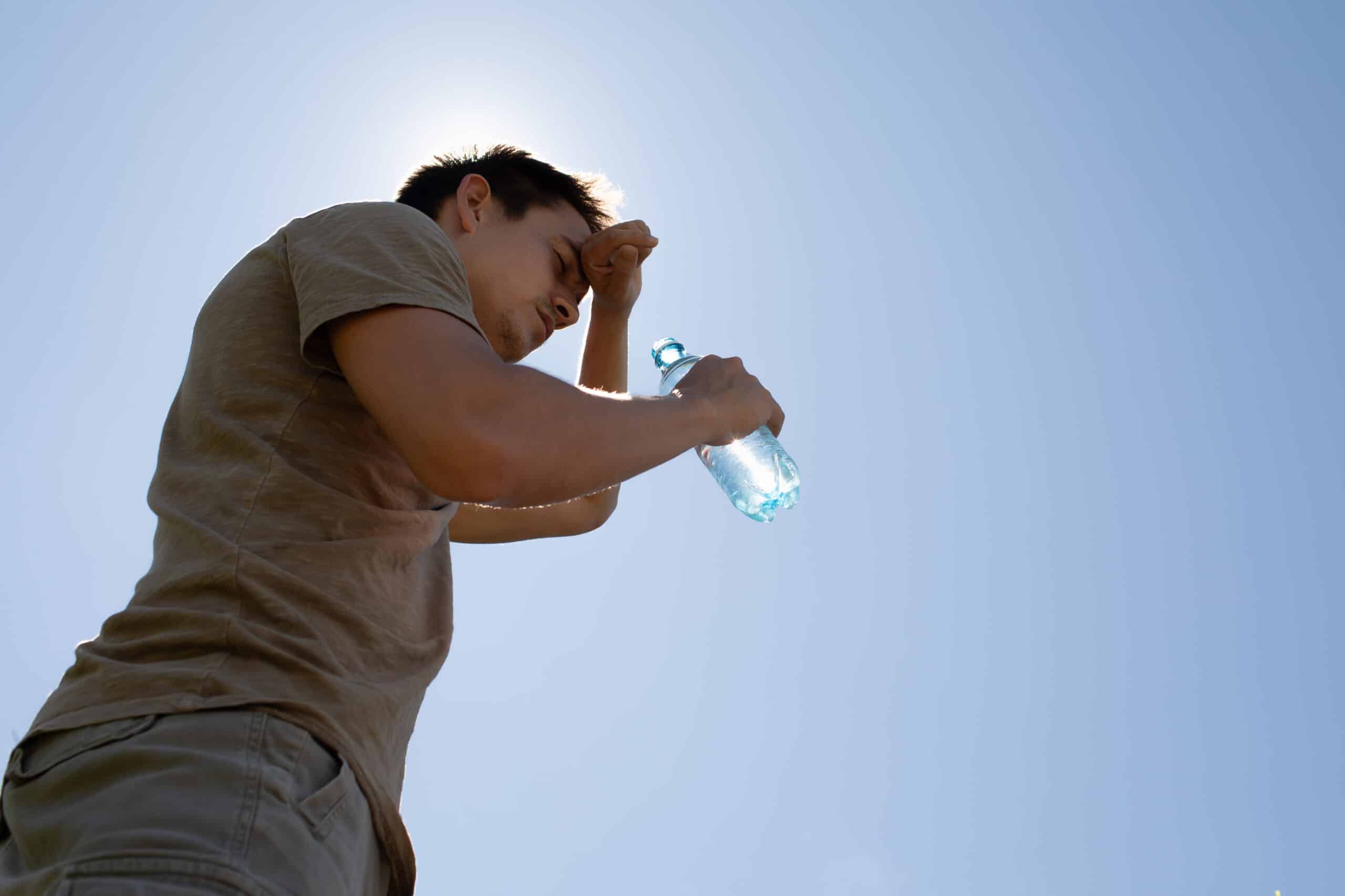 man drinking water feeling exhausted in the heat of the day